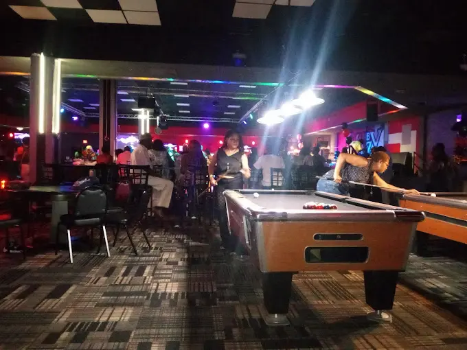 A group of people playing pool and drinking